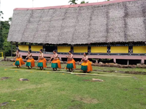 Local Palauan traditional dancers in front of a Bai, a men's house 