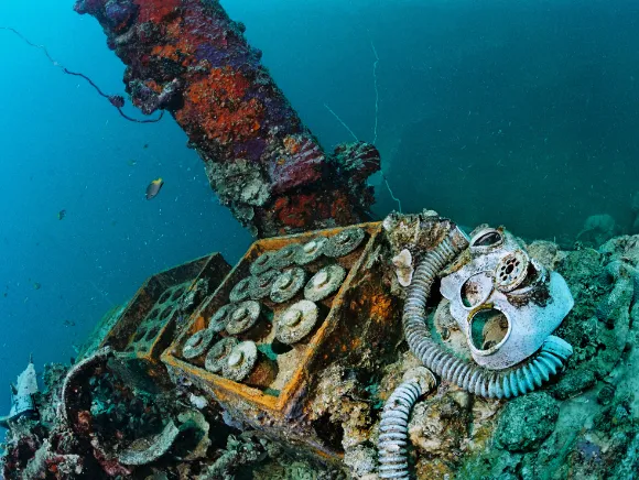 underwater photo of wreck parts like shells and gas masks in a wreck in Palau